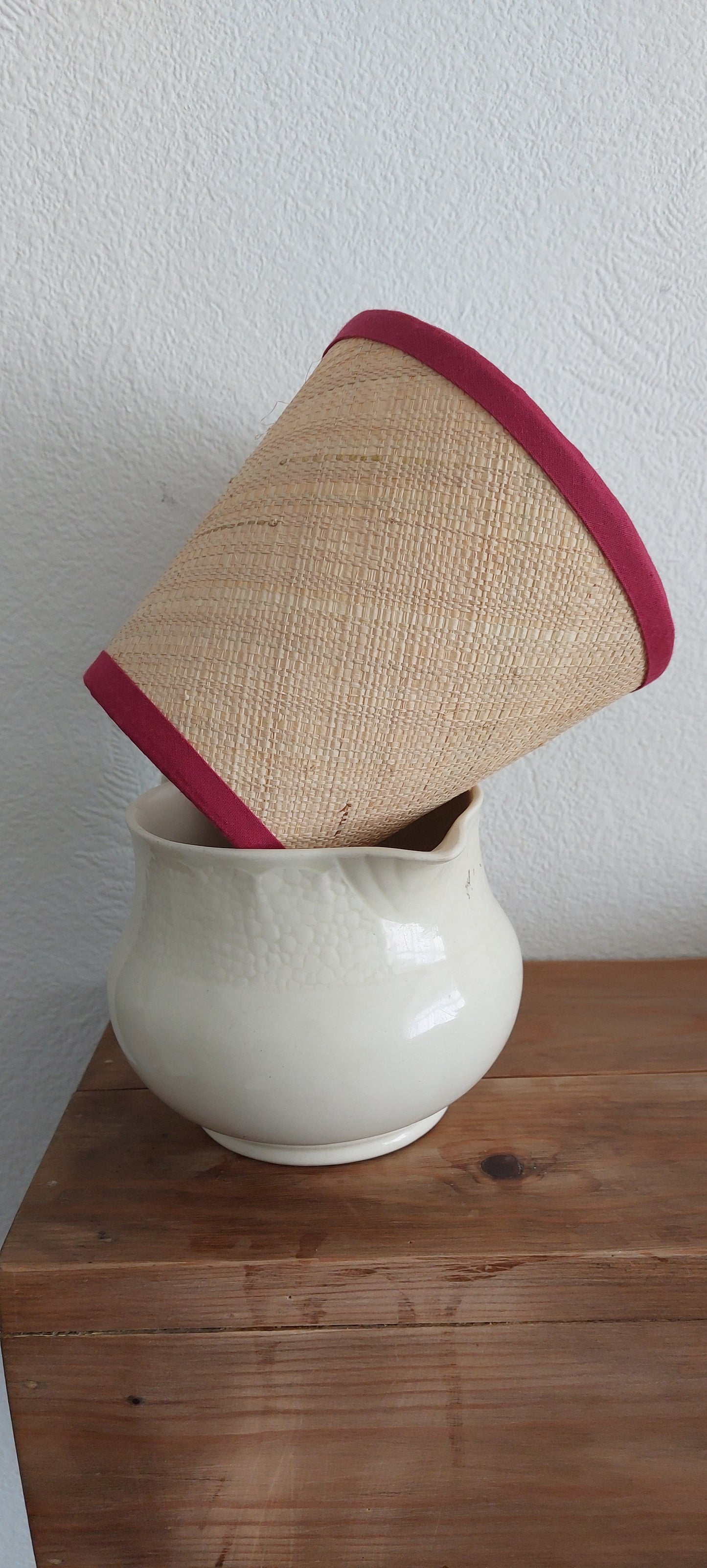 Raffia lamp shade with red trim.